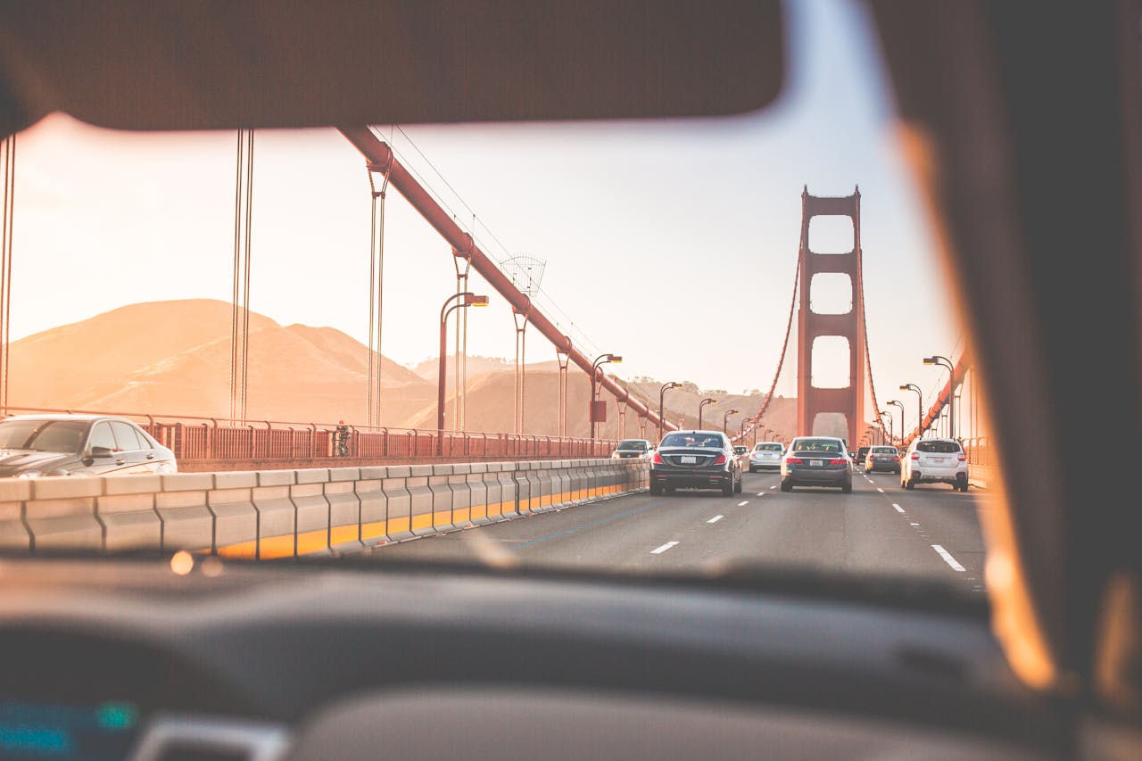 A scenic drive across San Francisco's iconic Golden Gate Bridge during sunset, capturing vehicles on the road.